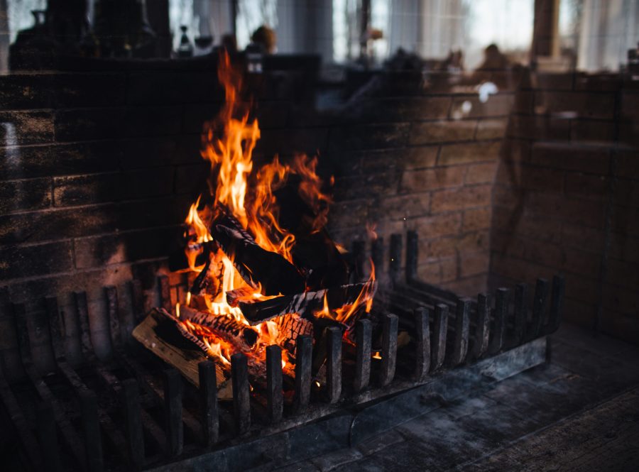 Beautiful bright fire flame. Blazing fire against brick wall background. Dark colours. Burning wood with smoke. Great heat. Burning embers