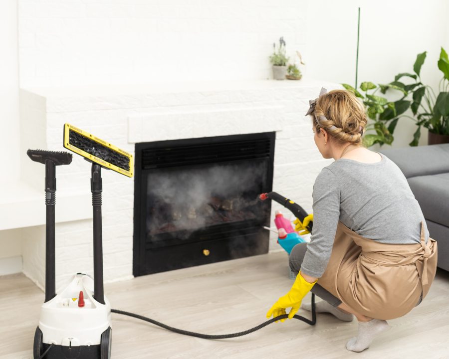 Woman using steam vapor cleaner in living room.