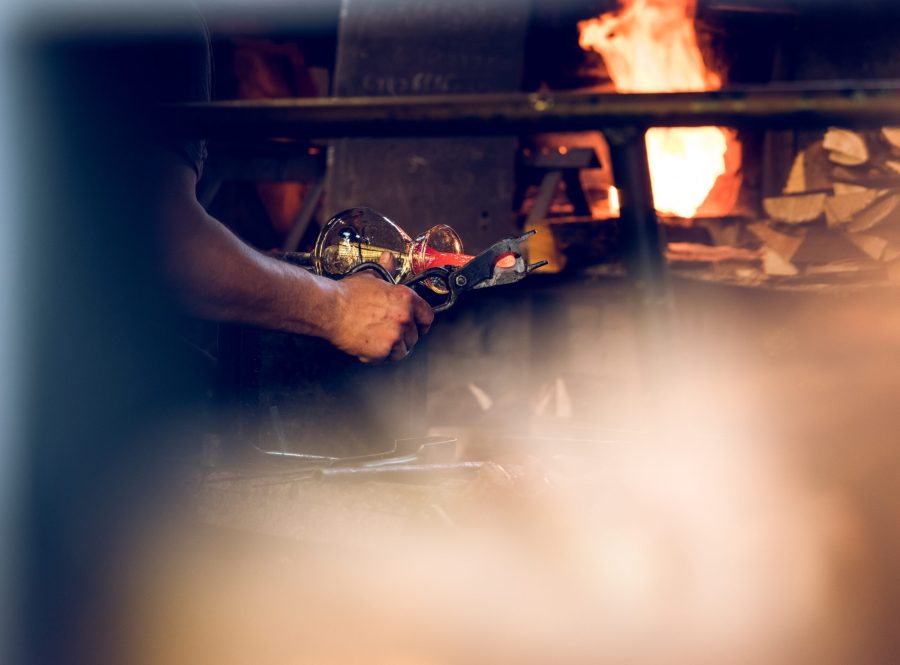 Crop unrecognizable craftsman working on factory and making glass decoration.